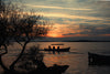 sun sets and silhouettes a boat on evening water
