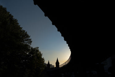 sun sets over the horizon above a bridge