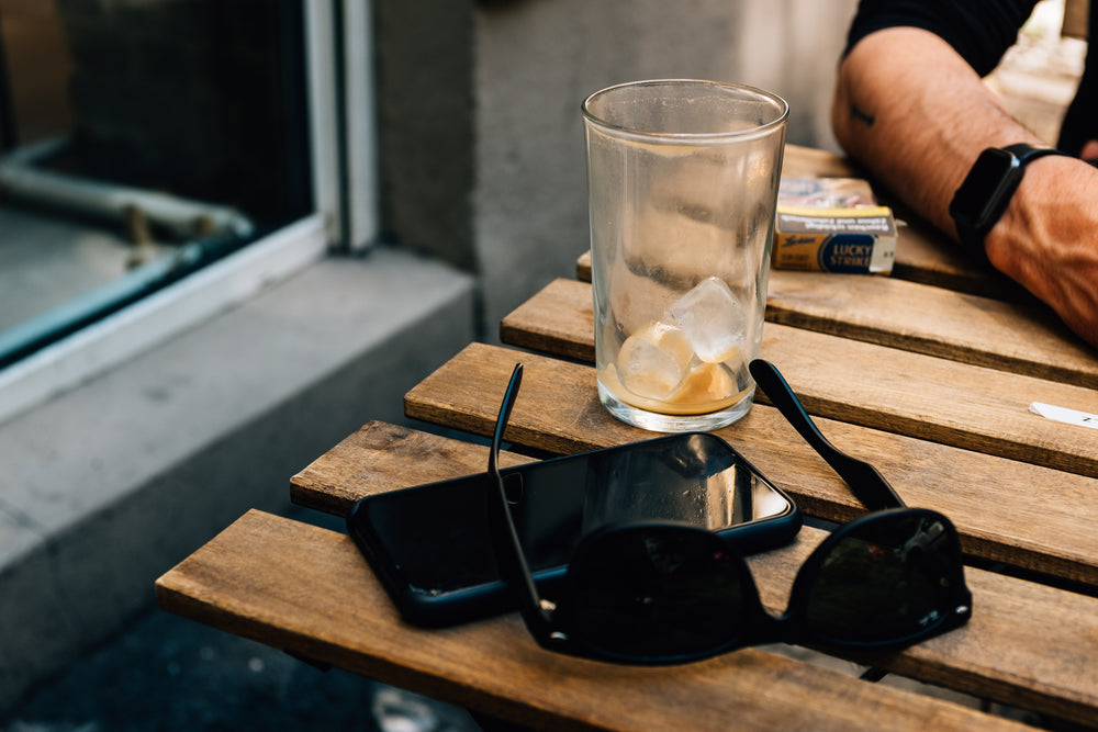 sunglasses and a cellphone on a wooden picnic table