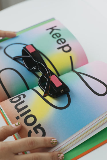 sunglasses lay in a open book held open by hands