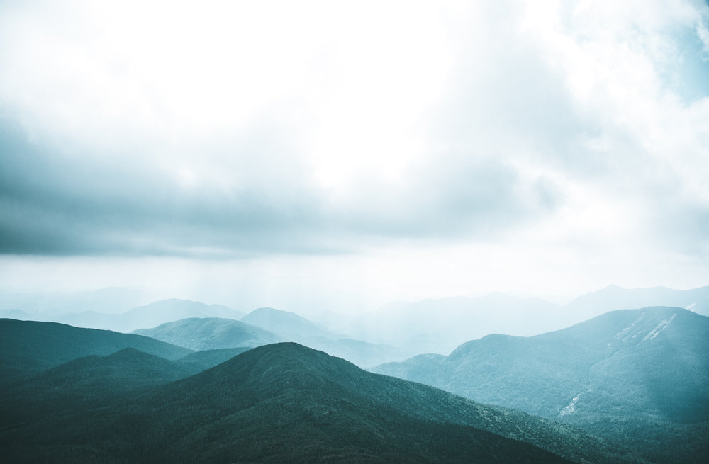 sunlight breaks through heavy clouds over hills