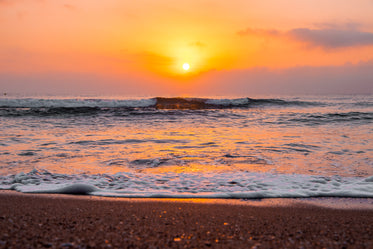 sunrise over wavy ocean on sandy beach