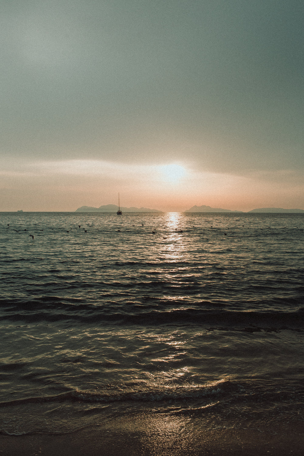 sunrise peaks through clouds on the shore