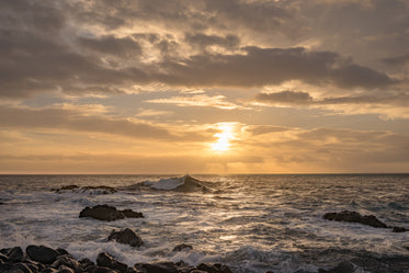 sunset as waves crash on rocky shore