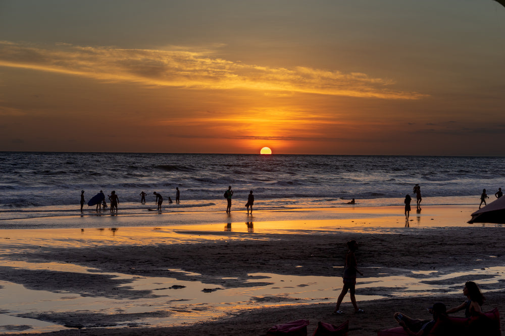 sunset at the beach while surfers get the last waves