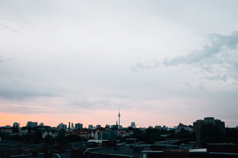 sunset burns pink against a grey sky over a city landscape