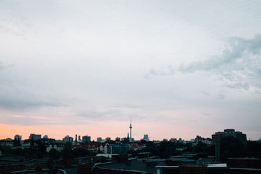 sunset burns pink against a grey sky over a city landscape