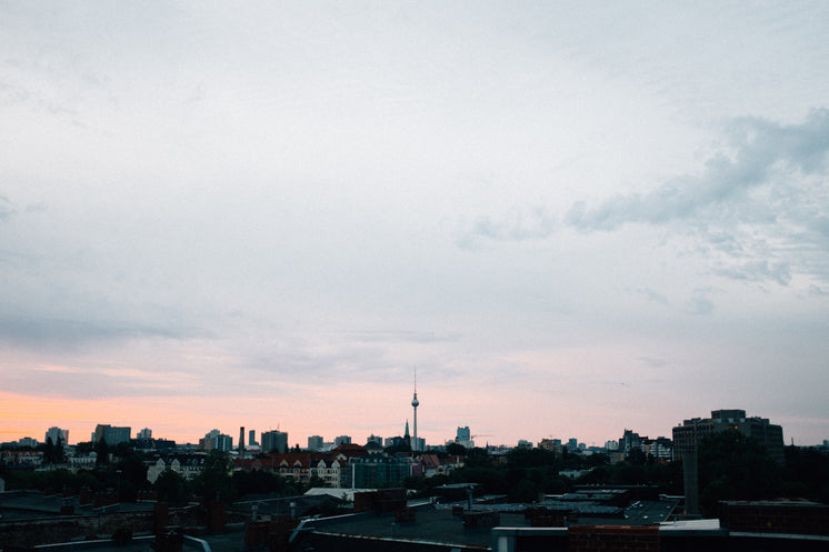 Sunset Burns Pink Against A Grey Sky Over A City Landscape