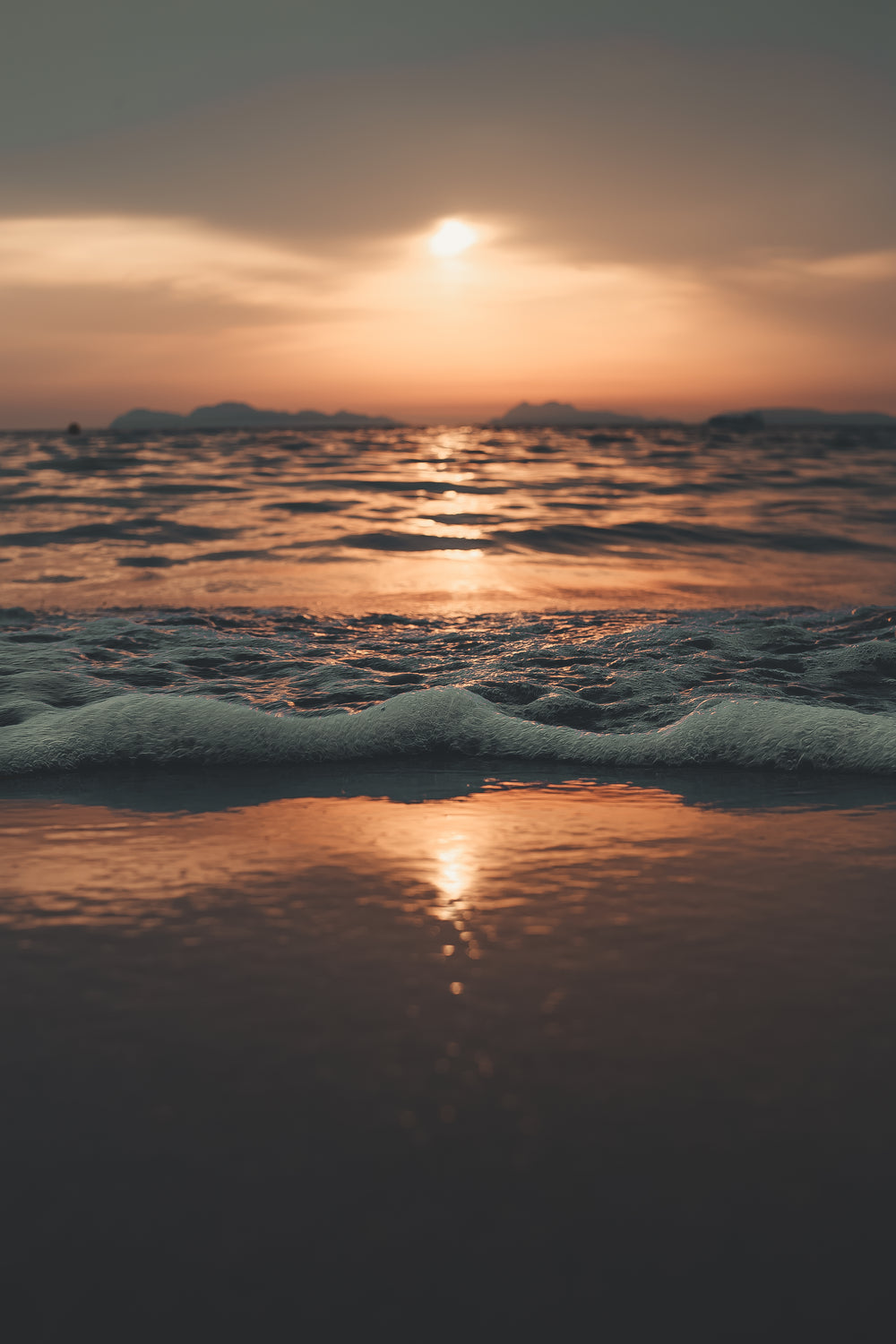 sunset casts gradient over foaming waves on the shore