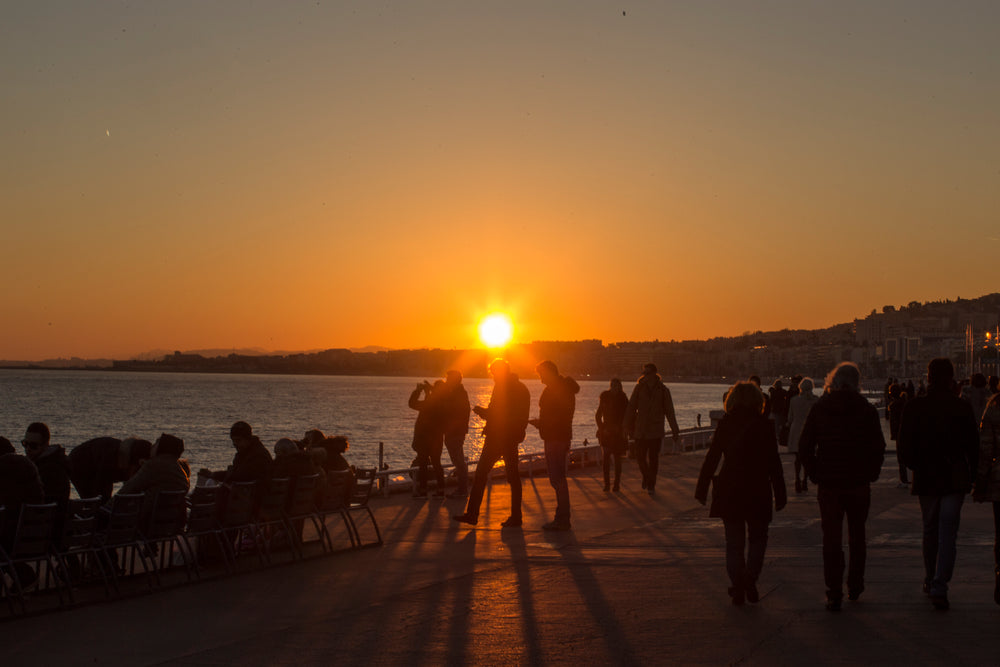 Crowd having fun on a ocean beach boardwalk of a vacation coast at dusk