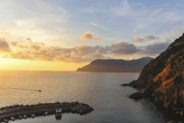 sunset on the water and a cliff in italy