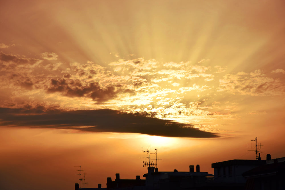 sunset over city rooftops with antennas