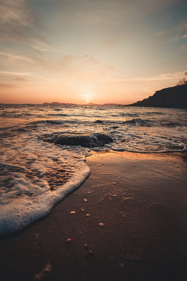 sunset tide spilling onto rocky beach