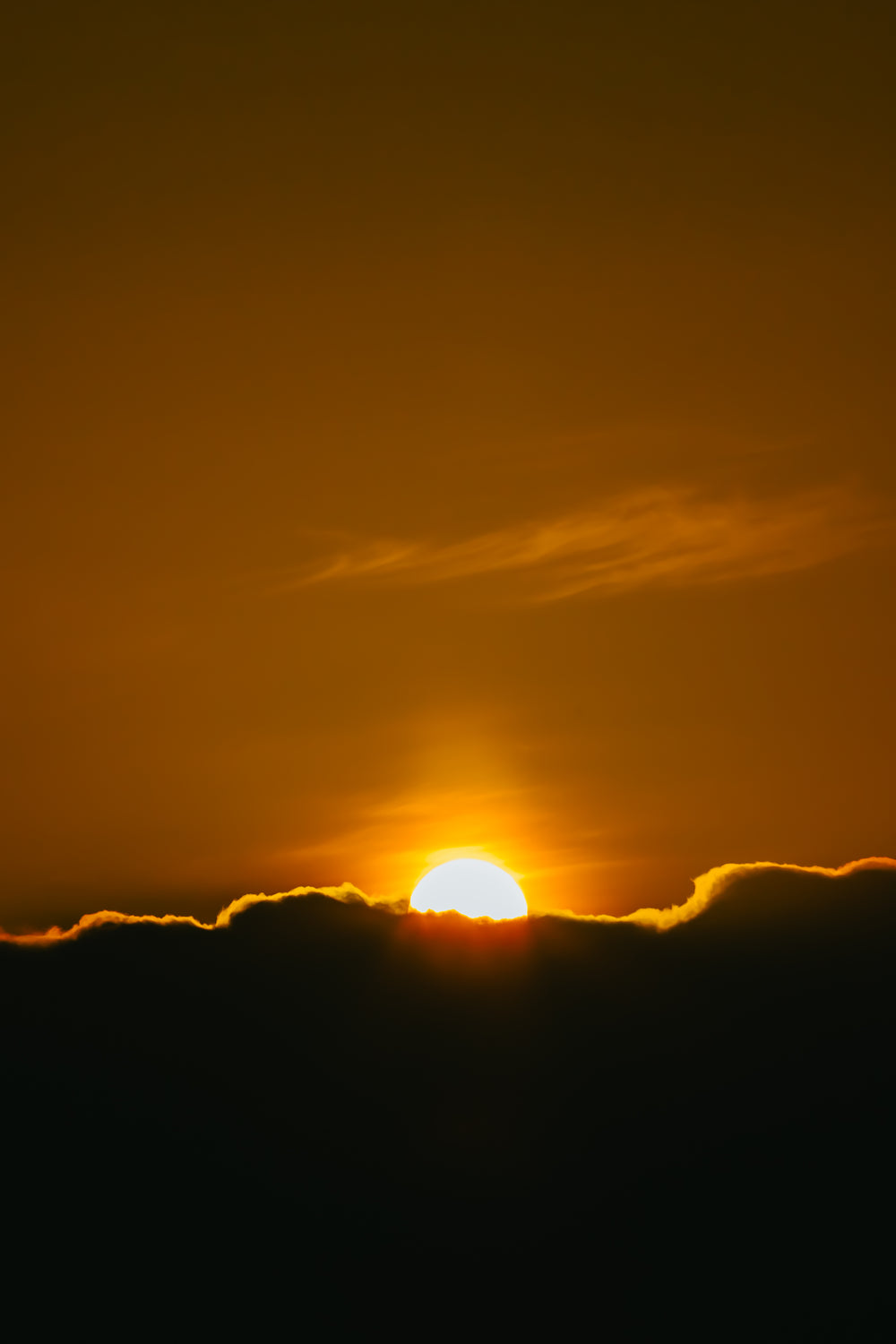 sunsets behind dark clouds in orange sky