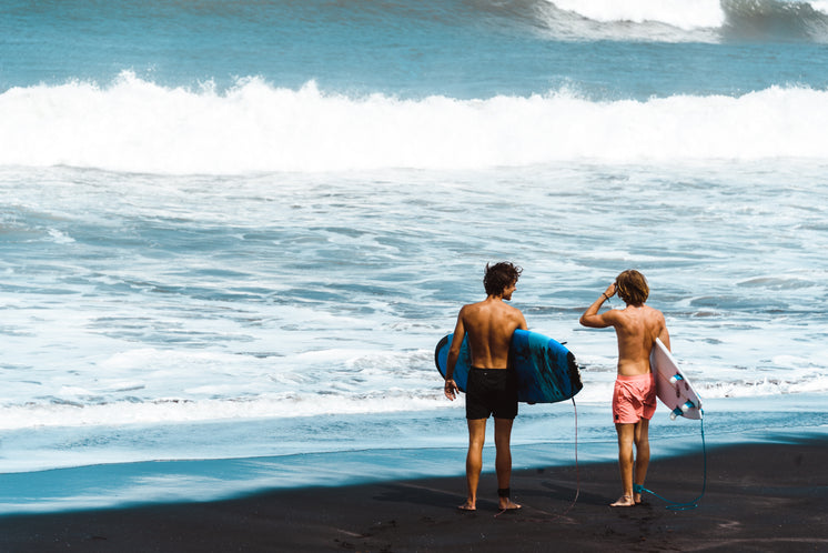 Surfers Stand On Shore