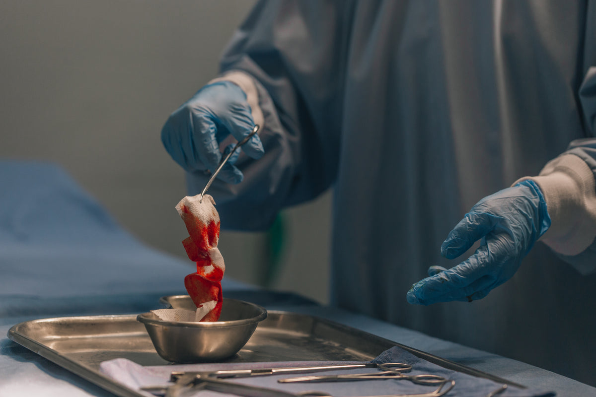surgeon transfers bloody gauze to dish