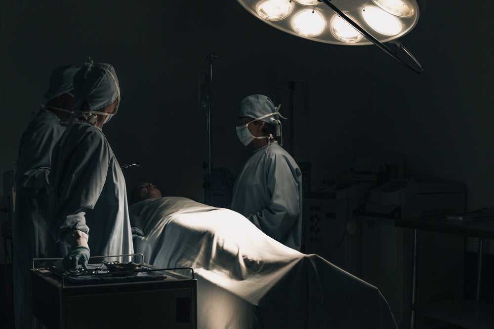 surgeons huddled around a patient on a hospital bed