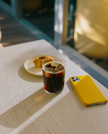 table with iced coffee and a cell phone face down