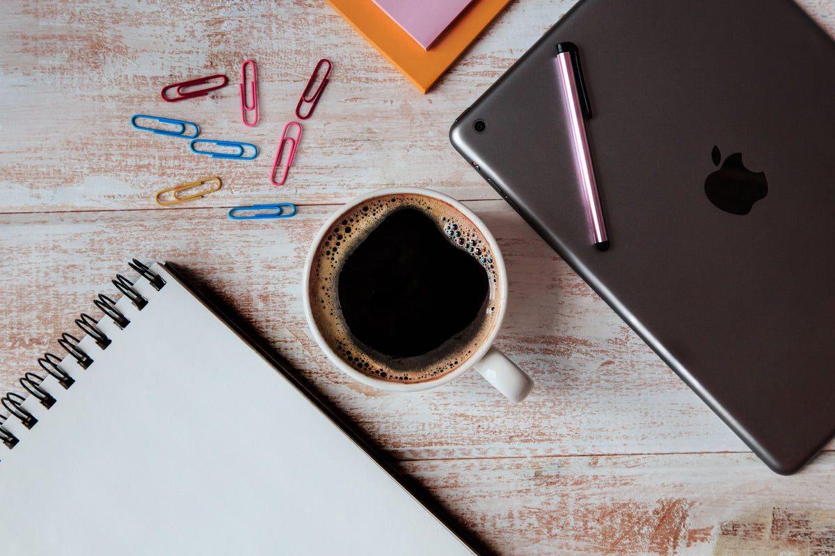 Tablet, coffee, and planning materials on a desk for a business website budgeting discussion