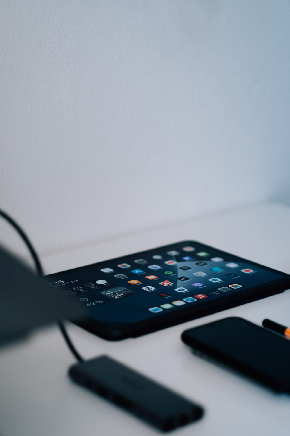 tablet lays on a white table with screen lit by app icons