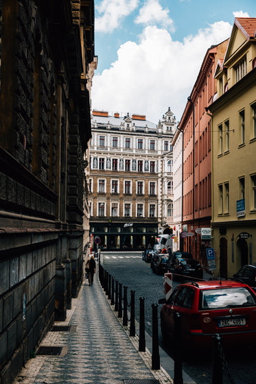 tall buildings surround a narrow street with parked cars