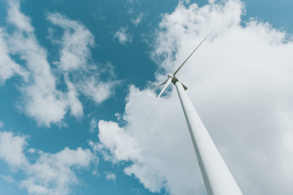 tall modern windmill against a blue sky with fluffy clouds