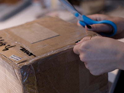 Taped Up Cardboard Box With A Person Holding Scissors