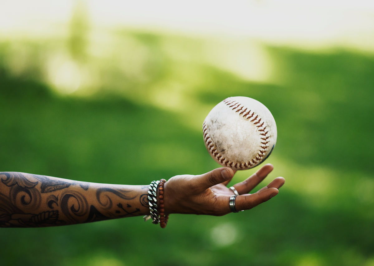 tattooed arm tosses baseball
