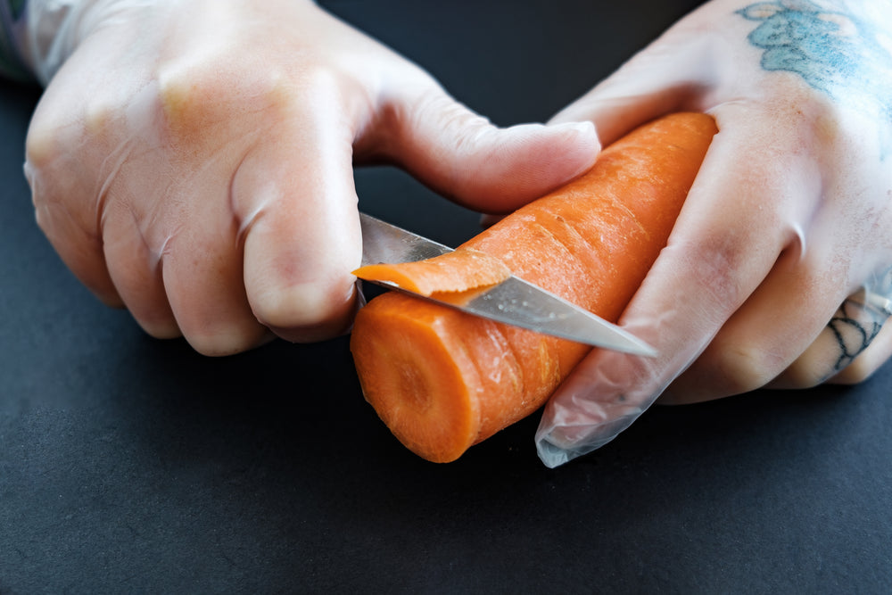 tattooed hands cut a carrot