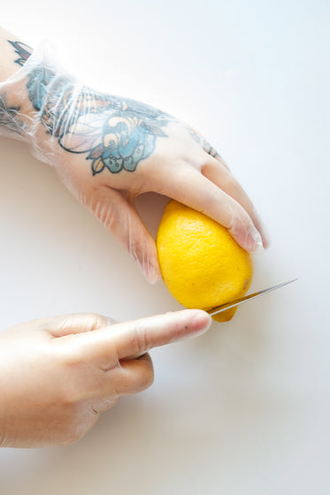 tattooed hands cut a lemon
