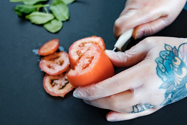 tattooed hands preparing food with gloves