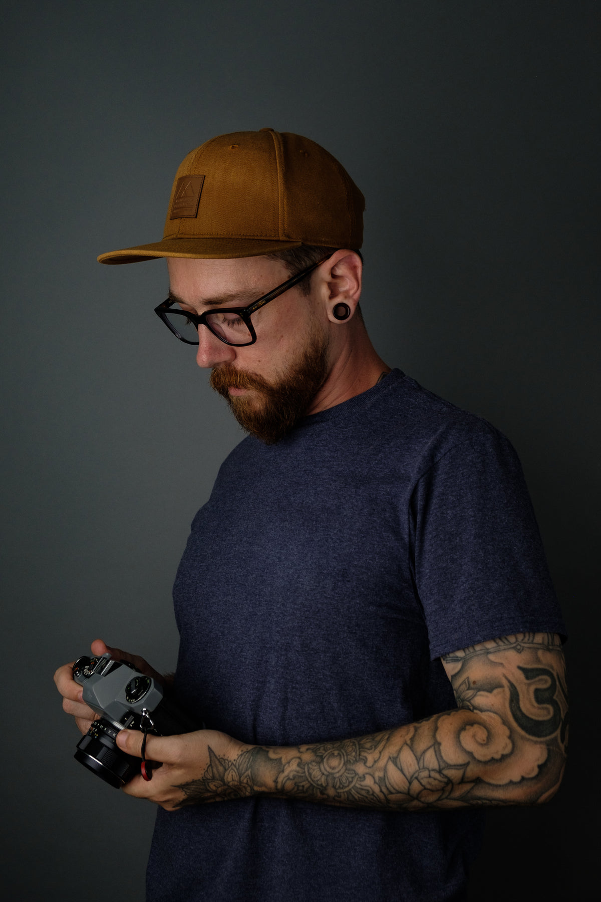 tattooed man holding film camera
