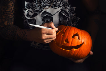 tattooed woman carves eyes into smiling jack o lantern