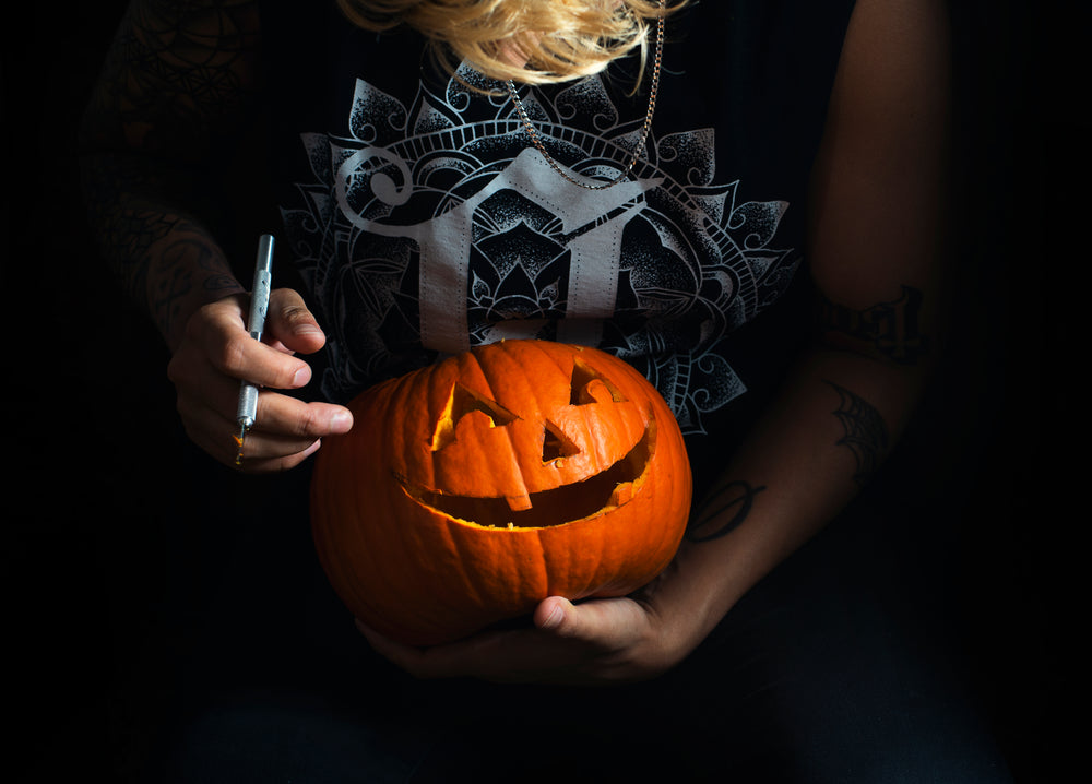 tattooed woman carving halloween pumpkin