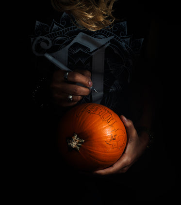 tattooed woman holds festive jack o lantern