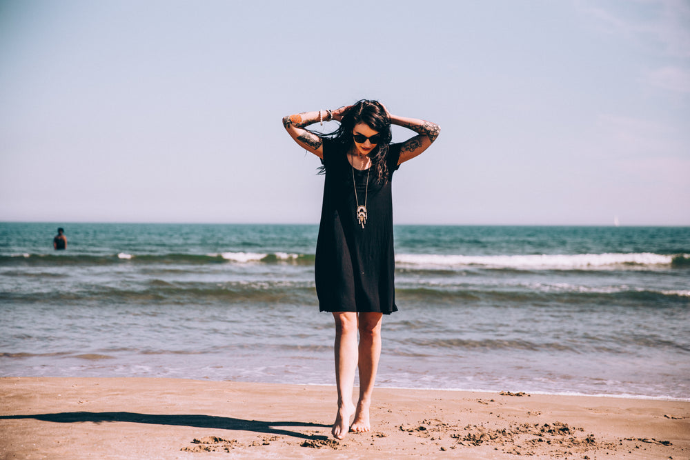 tattooed woman on beach with toes in the sand