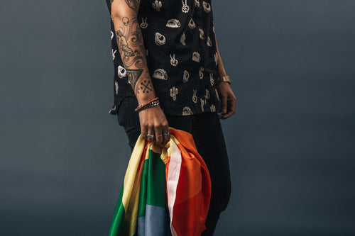 tattoos bracelets and rings holding pride flag
