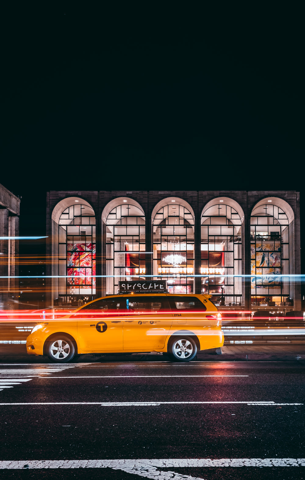 taxi races past urban gallery at night