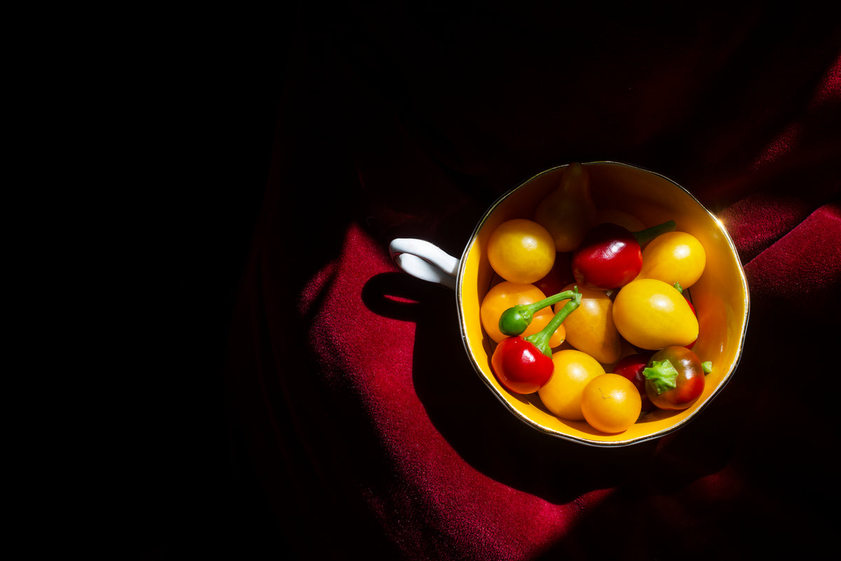 tea cup with hot peppers and yellow tomatoes on red