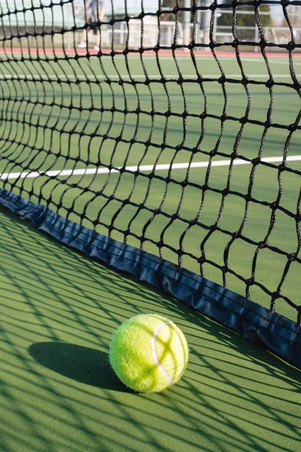 tennis ball lays net to a tennis net