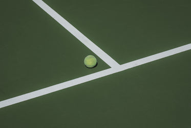 tennis ball sits in the corner of the tennis court