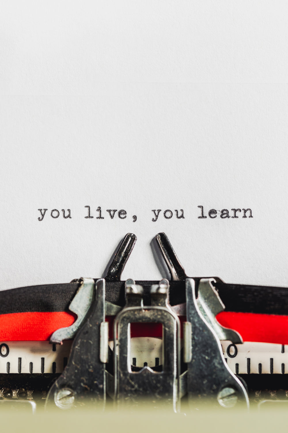 text on typewriter states you live, you learn