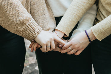 the arms of people in sweaters holding hands