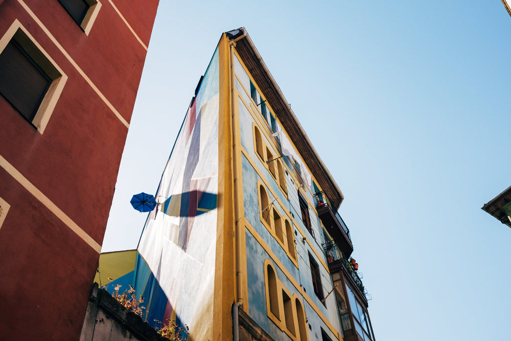 the corner of a colorful building splits the blue sky