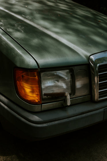 the front headlight of a dark green car