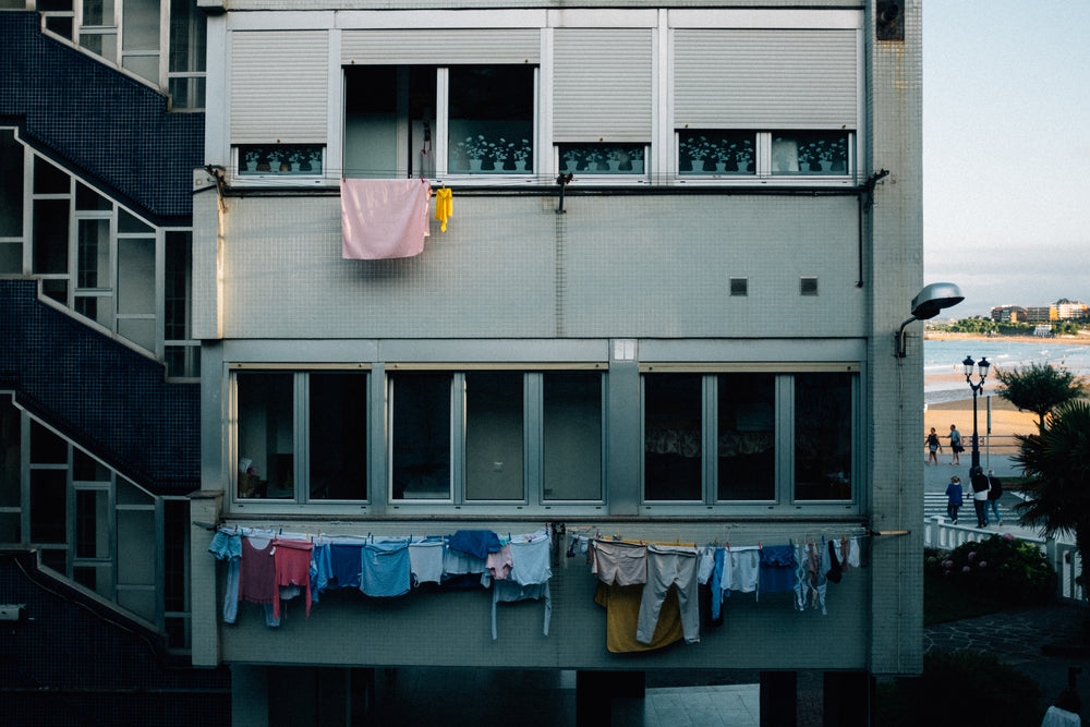 the grey face of an apartment block draped in clothes lines