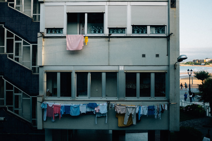the grey face of an apartment block draped in clothes lines - Updated Miami