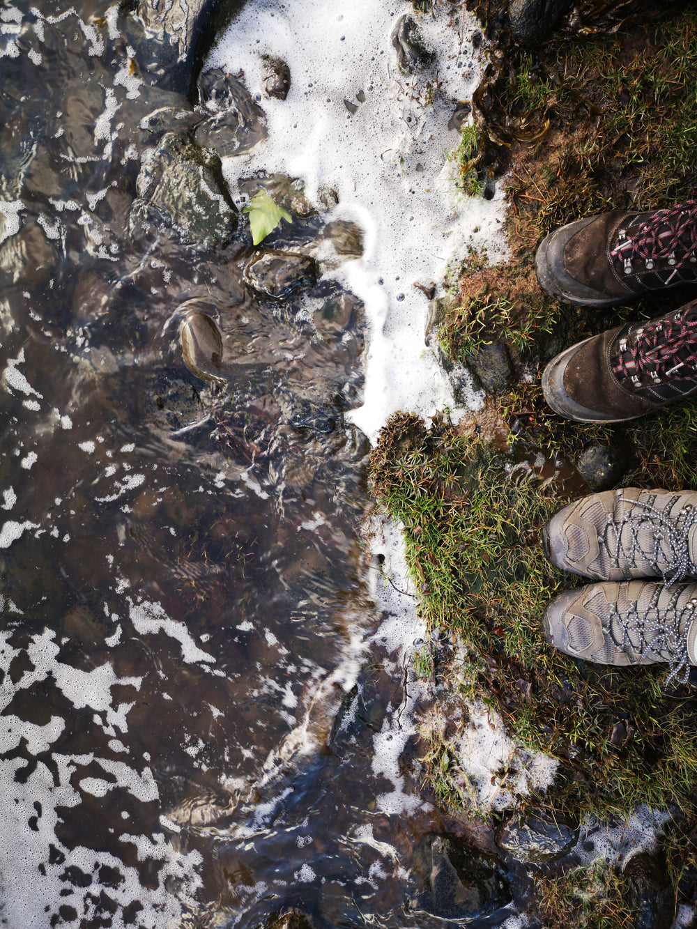 the river meets the banks where two pairs of boots are