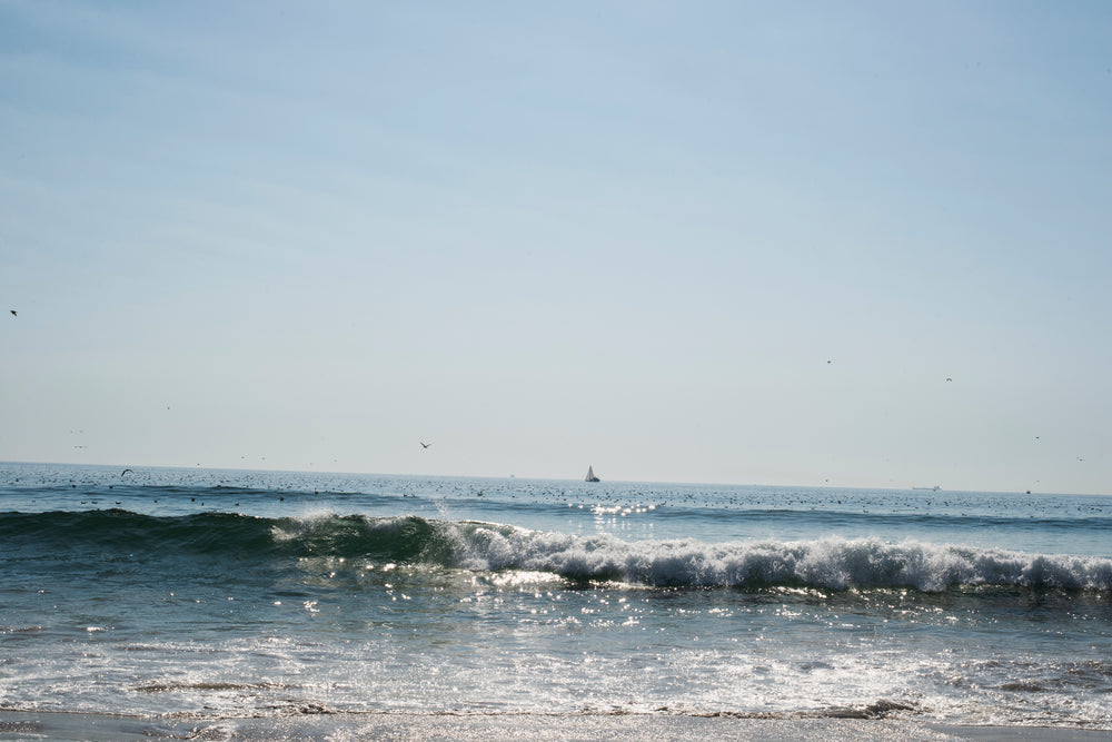 the sea crashing into shore on a sunny day