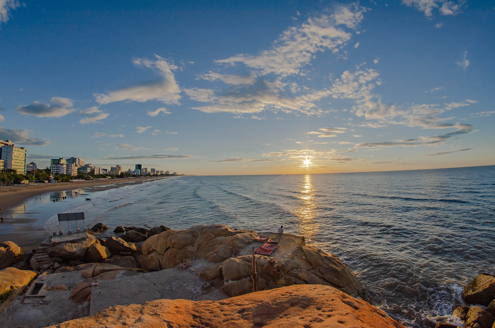 the setting sun over still water on a city coast